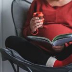 A pregnant woman reading a book to her baby.