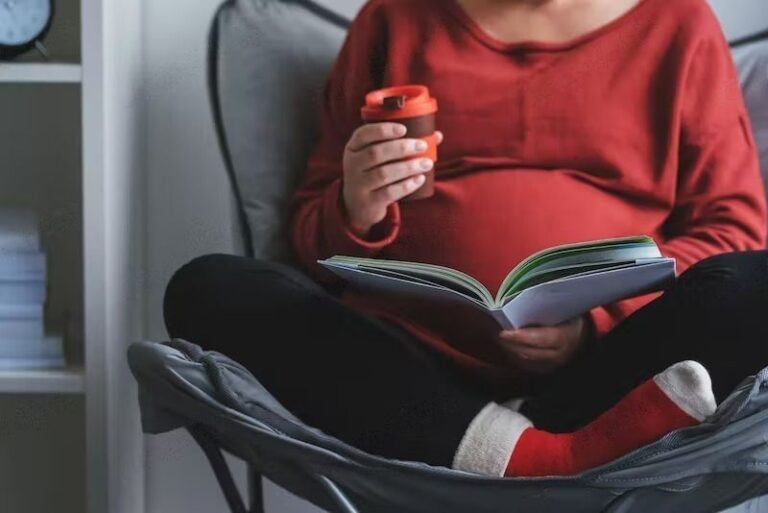 A pregnant woman reading a book to her baby.