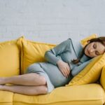 beautiful pregnant woman sleeping on yellow sofa at home transformed