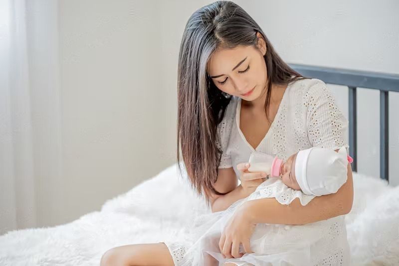 Tips for Breast Milk Storage. A beautiful mother feeding baby with bottle of milk