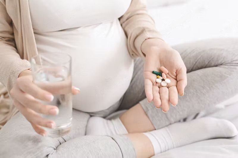 What To Eat When Pregnant? Expectant woman holding bunch of pills and glass of water