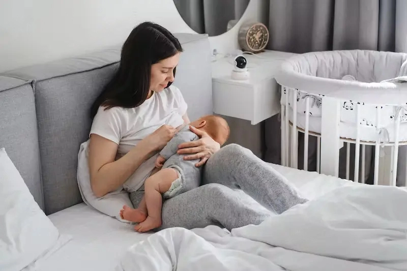 Benefits of Breastfeeding - Breastfeeding mama with cute kid at home in bed