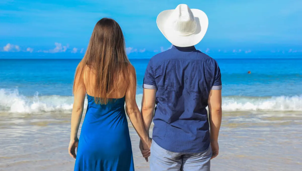 Vacation couple walking on beach together in love holding around each other
