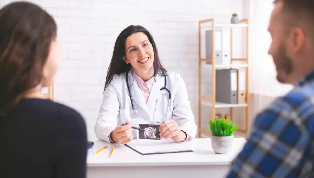 doctor explaining pregnancy diagnosis with ultrasound picture to young couple at clinic