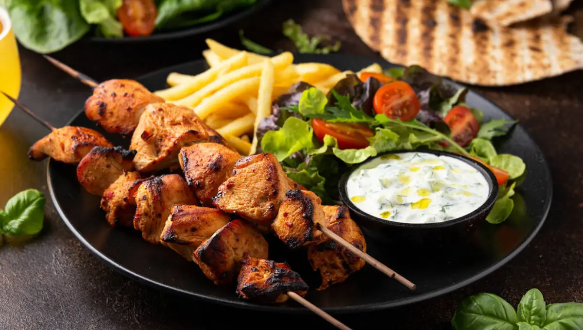 Chicken fillet souvlaki, kebabs on skewers with potato chips, salad and fresh home made tzatziki