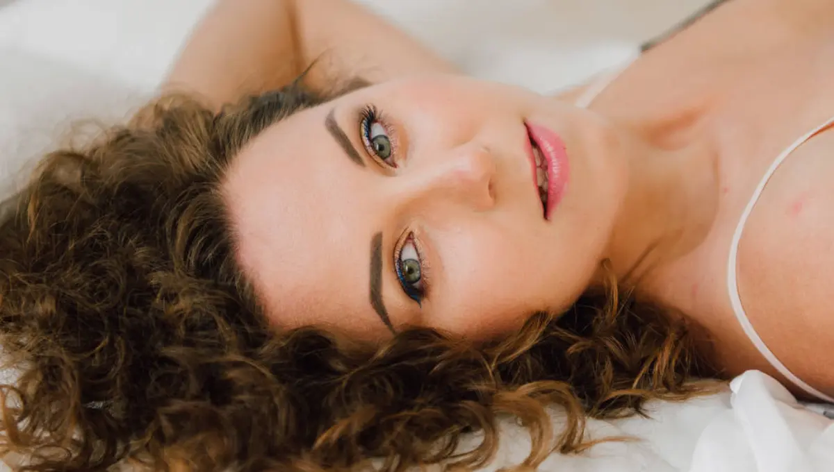 A smiling beautiful woman lying on a bed