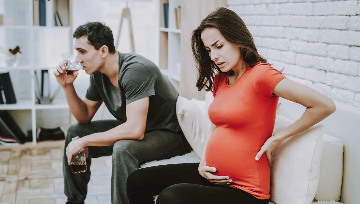 man drinking alcohol besides her pregnant wife