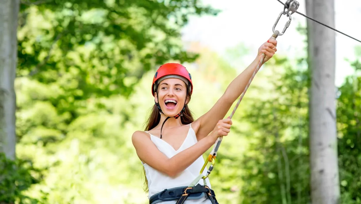 a happy and excited woman riding a zipline