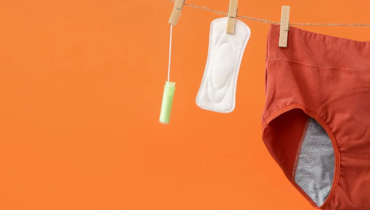 Period underwear, pads, and tampons hanging on a rope against an orange background