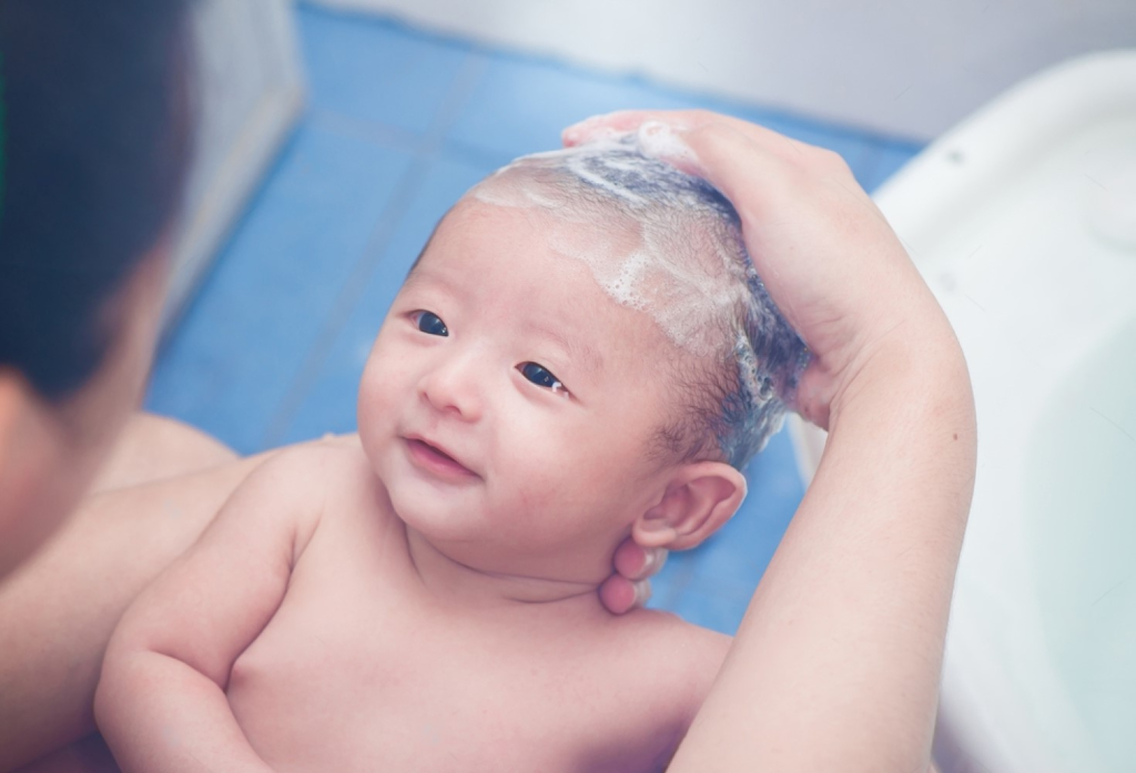 a baby looking at her mom and is being shampooed