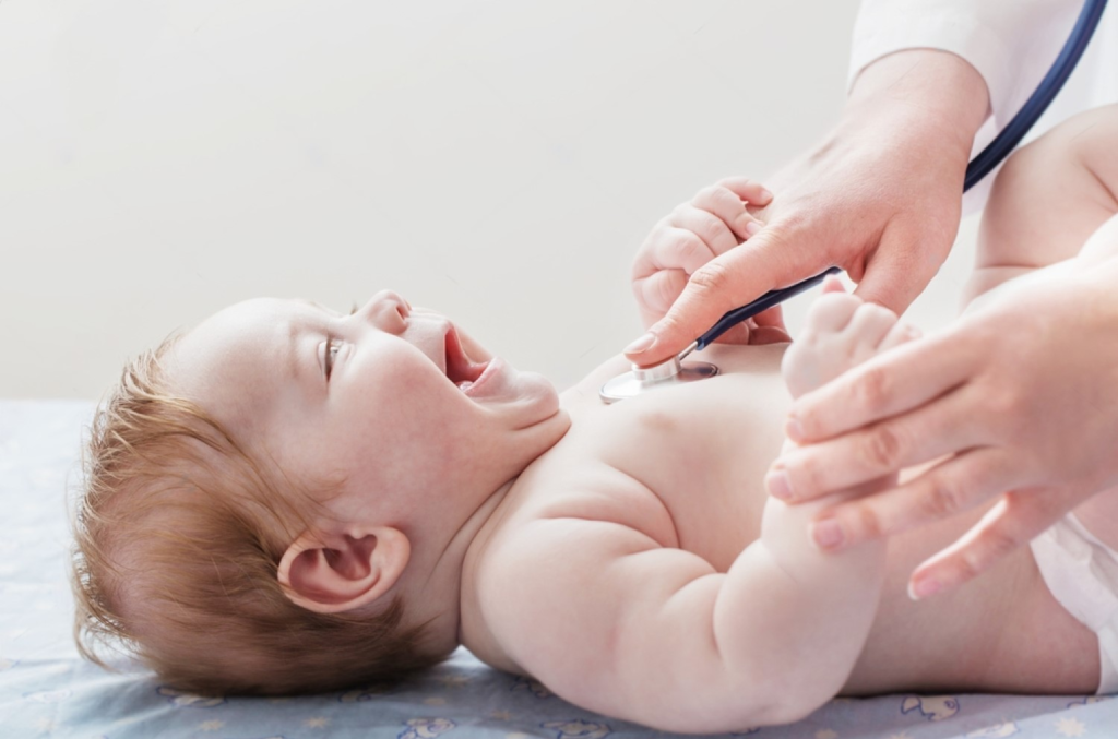 a happy smiling baby being checked by a doctor