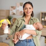 a mother showing the breast pump whle holding her baby in her arms