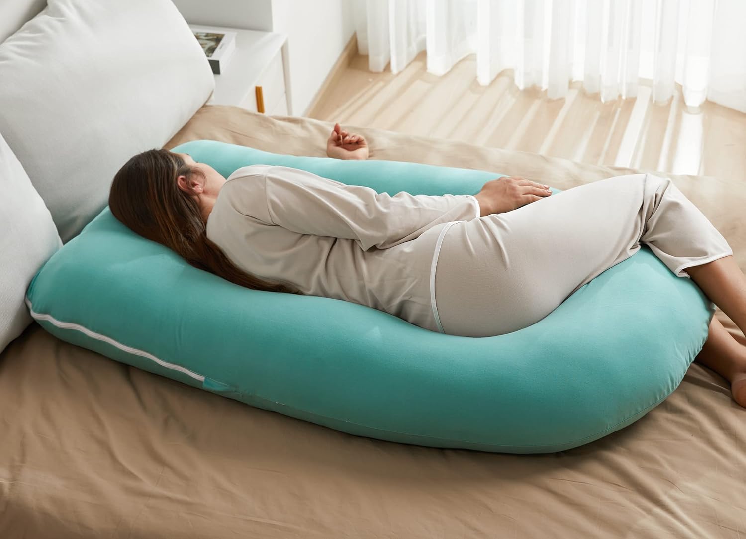 Pregnant woman sleeping comfortably on the Momcozy U-shaped pregnancy pillow with full body support